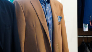 Abiti da cerimonia uomo taglie comode: dettaglio di giacca elegante beige su manichino in negozio.