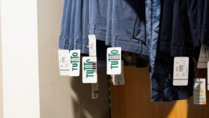 Jeans taglie comode uomo: dettaglio di pantaloni in denim appesi con cartellino Tutto Abbigliamento.