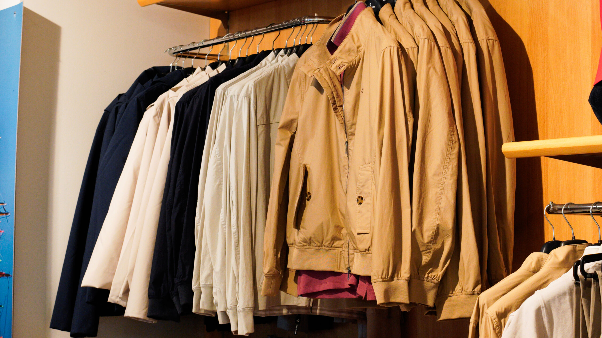 Giacche e camicie uomo taglie forti: stand espositivo con capispalla leggeri beige e blu per la mezza stagione.