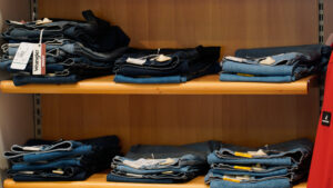 Jeans uomo taglie forti: espositore con pantaloni in denim Wrangler piegati su ripiani in legno.