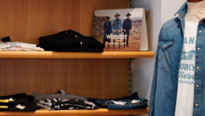 Jeans e camicie uomo taglie forti: espositore con abbigliamento casual estivo Wrangler e brand assortiti.