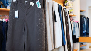 Pantaloni taglie comode donna: dettaglio di pantaloni estivi scuri con strass esposti in negozio.