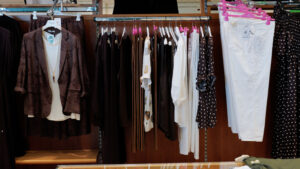 Completi eleganti taglie comode: stand con giacche marroni, camicie bianche e pantaloni leggeri.