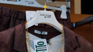 Accessori e abbigliamento curvy donna: dettaglio di collana su blusa marrone in espositore.