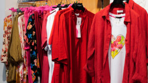 Abiti estivi taglie forti colorati: espositore con capi in rosso acceso e maglie con stampe.