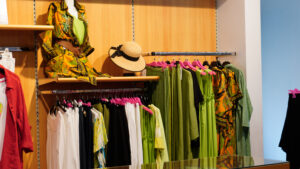 Vestiti estivi curvy colorati: espositore con completi verde acido, giallo e fantasie floreali.