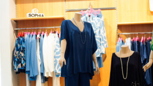 Abiti donna taglie grandi: espositore con vestiti blu e accessori moda per taglie comode.