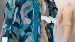Moda mare e vestiti estivi curvy: manichino con abito a fantasia geometrica azzurra e verde.