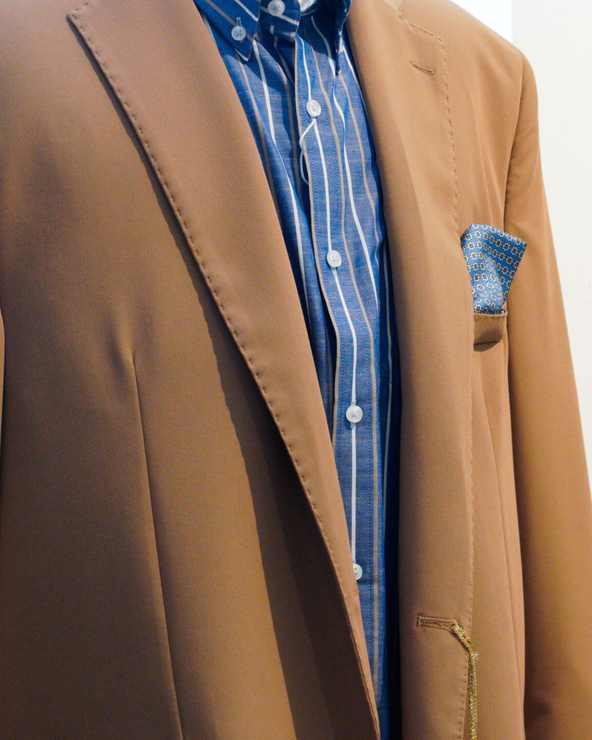 Abiti da cerimonia uomo taglie comode: dettaglio di giacca elegante beige su manichino in negozio.