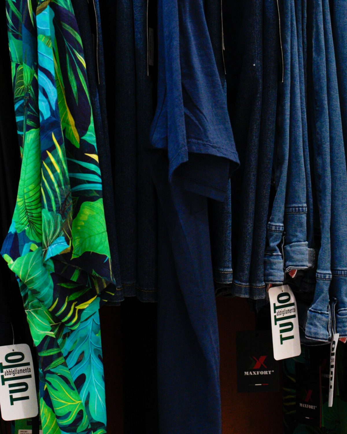 Camicie estive uomo taglie forti: stand con camicie a vistosa fantasia tropicale verde e azzurra.
