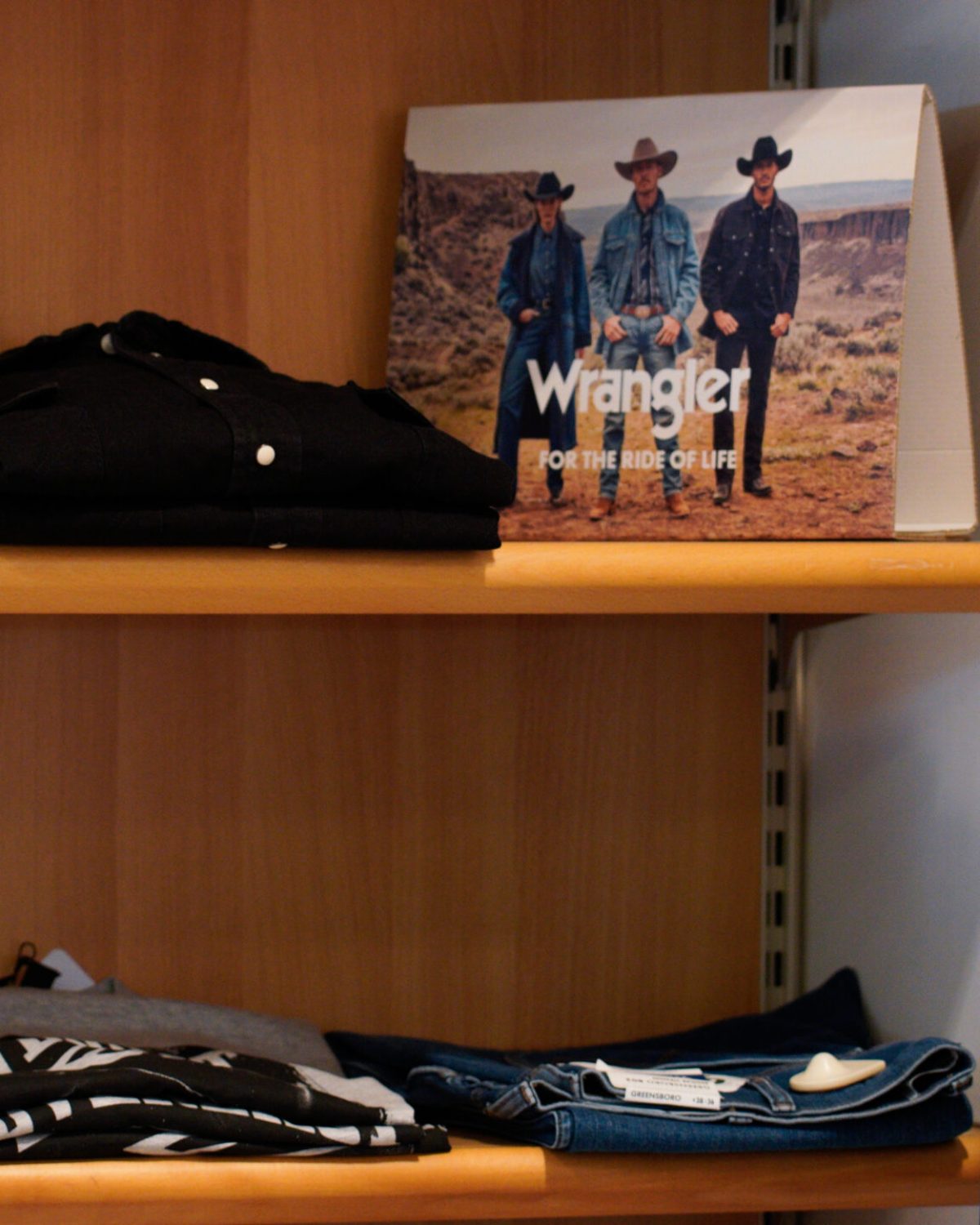 Jeans e camicie uomo taglie forti: espositore con abbigliamento casual estivo Wrangler e brand assortiti.