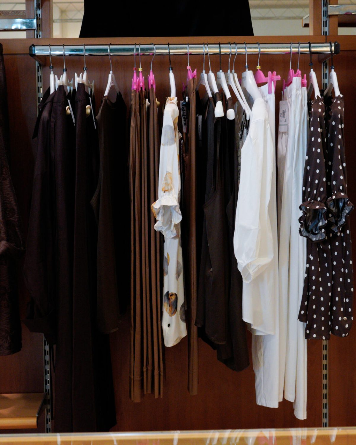Completi eleganti taglie comode: stand con giacche marroni, camicie bianche e pantaloni leggeri.