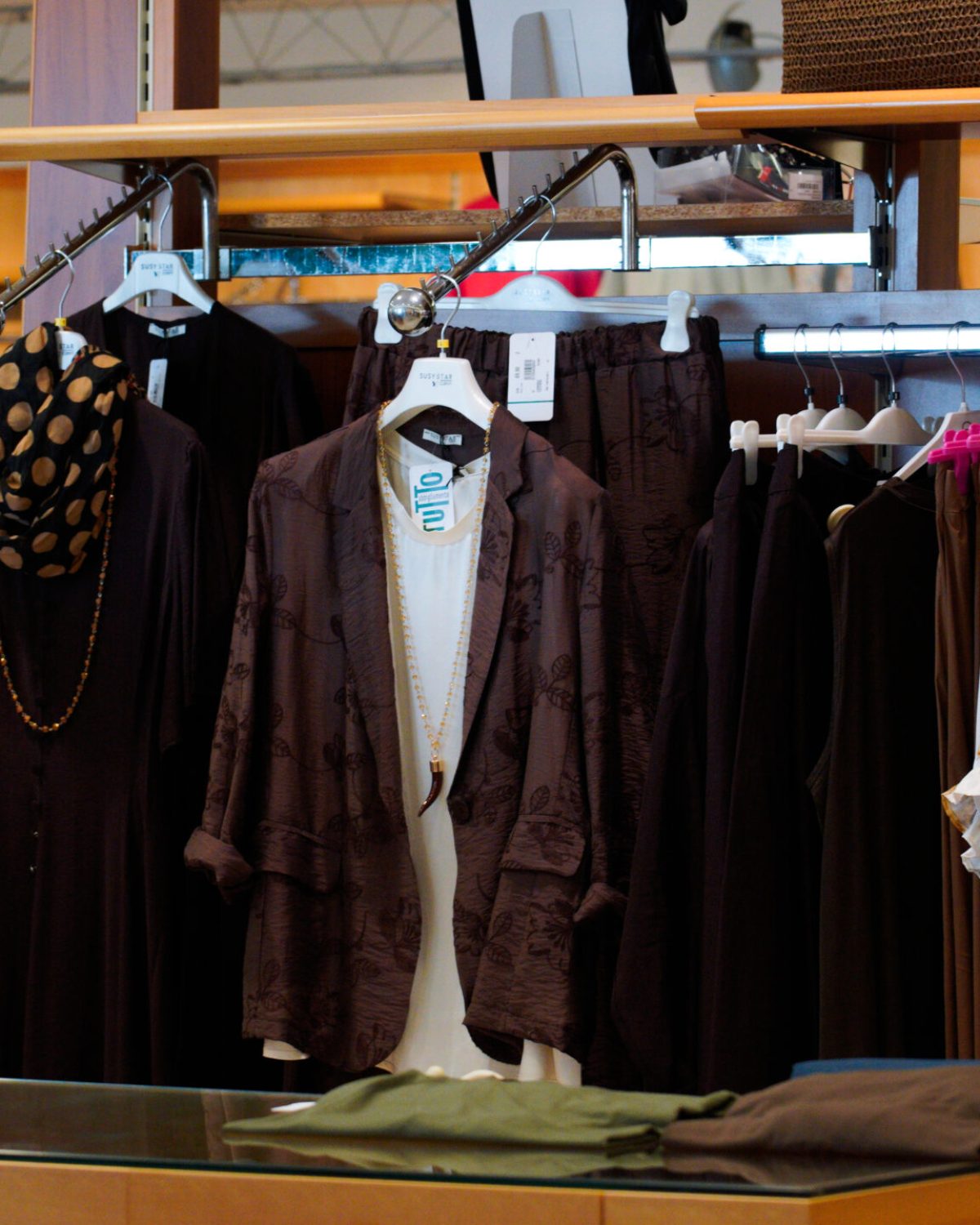 Moda curvy coordinati estivi: stand con pantaloni, bluse e giacche leggere in colori della terra.