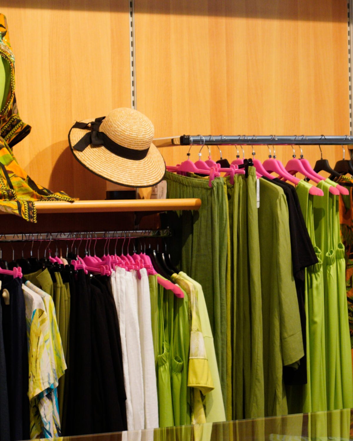 Vestiti estivi curvy colorati: espositore con completi verde acido, giallo e fantasie floreali.