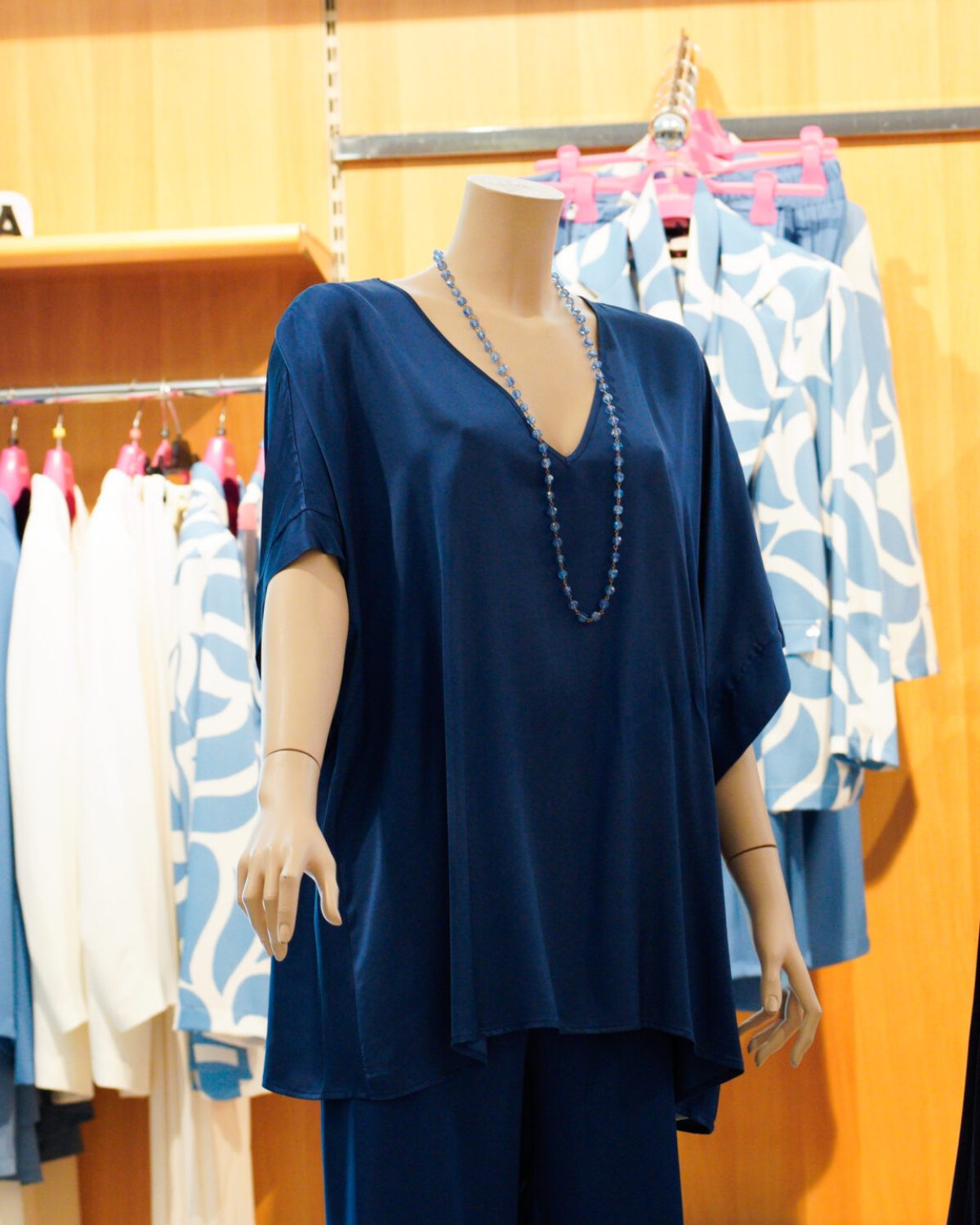 Abiti donna taglie grandi: espositore con vestiti blu e accessori moda per taglie comode.