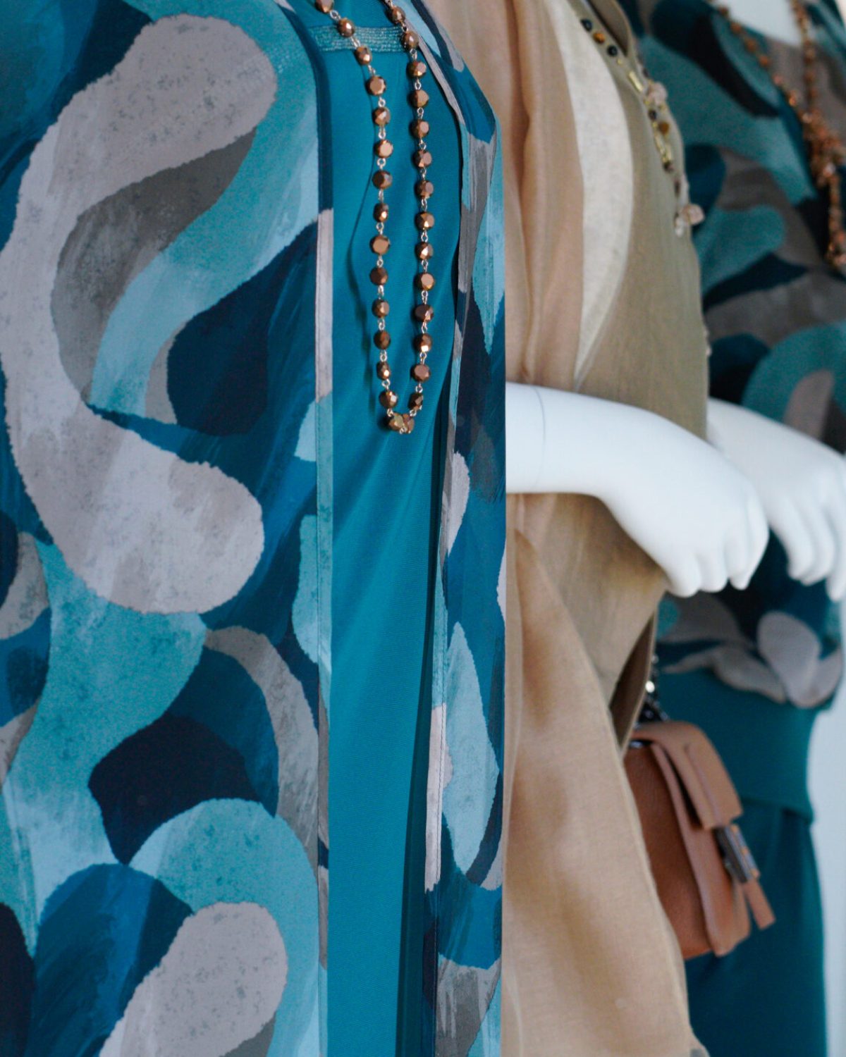 Moda mare e vestiti estivi curvy: manichino con abito a fantasia geometrica azzurra e verde.
