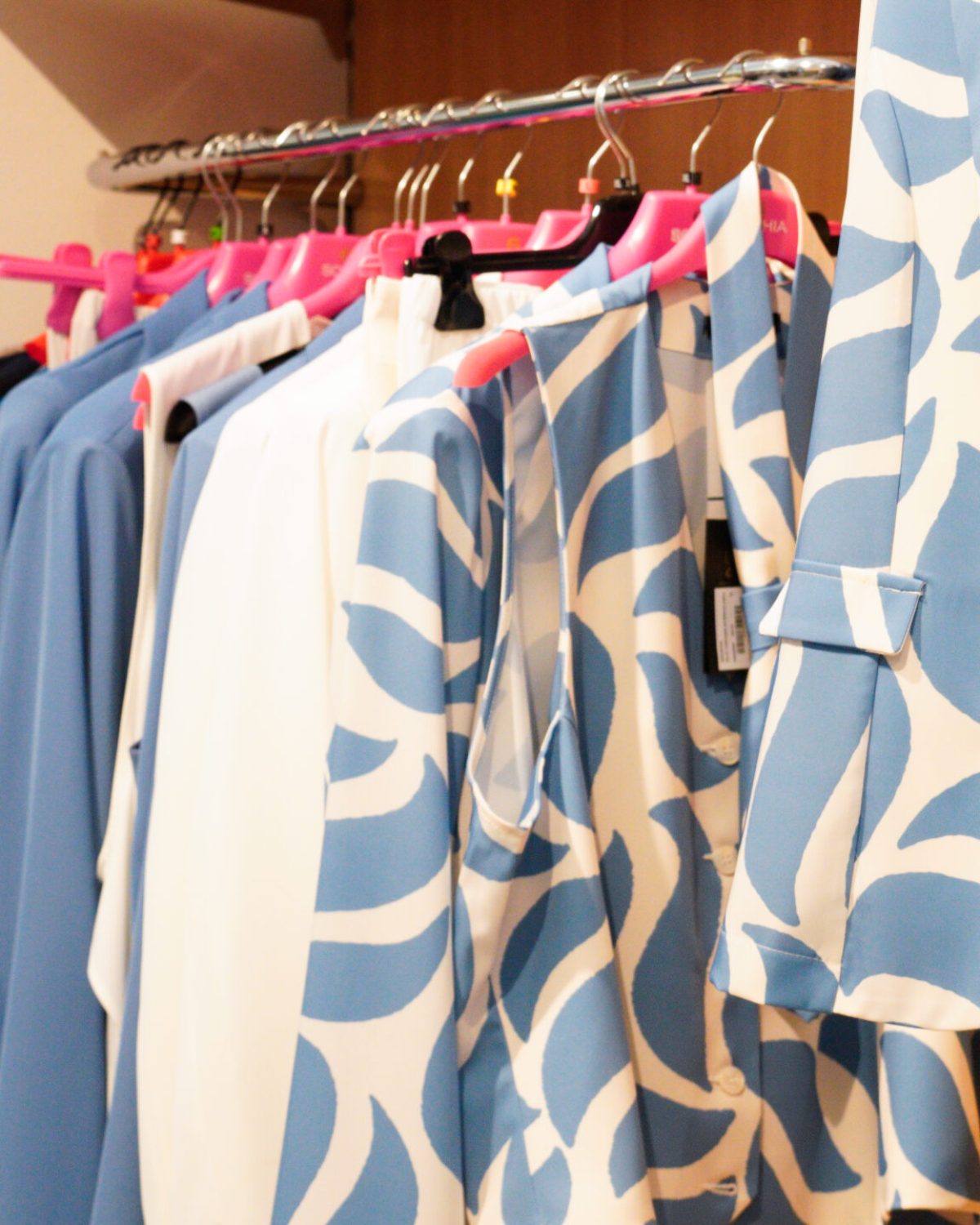 Abbigliamento curvy online: stand con abiti e bluse a motivi geometrici azzurri e bianchi.